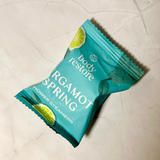 Teal package of 'Argamot Spring' shower steamers on a light-colored tiled floor.