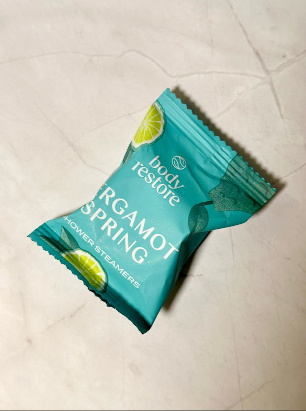 Teal package of 'Argamot Spring' shower steamers on a light-colored tiled floor.